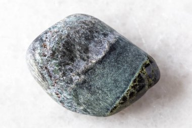 Rusya 'nın Kola Yarımadası yakınlarındaki beyaz mermer zemin üzerinde diopside minerali bulunan yuvarlanmış richterite kayası örneği