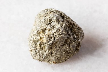 Beyaz mermer zemin üzerinde kesilmemiş pirit taşı örneği yakın plan