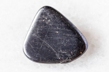 Beyaz mermer arka planda cilalanmış ilmenit minerali örneği. Güney Urallar, Rusya 'dan yakın plan.