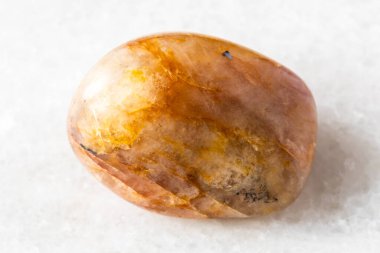 Yuvarlanan turuncu kuvars taşı örneği beyaz mermer zemin üzerinde Rusya, Güney Urallar 'dan yakın plan