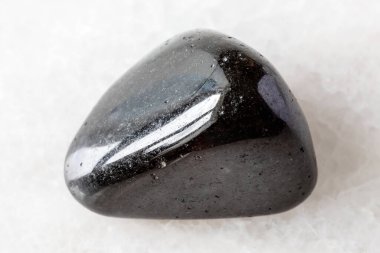 Madagaskar yakınlarında beyaz mermer arka planda yuvarlanmış siyah turmalin minerali örneği