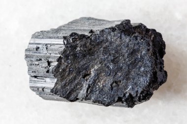 Beyaz mermer arka planda işlenmemiş siyah turmalin schorl minerali örneği yakın plan