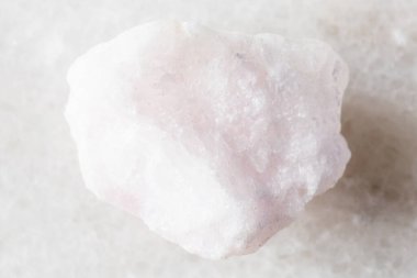 Beyaz mermer arka planda ham pembe aragonit minerali örneği. Yakın plan.