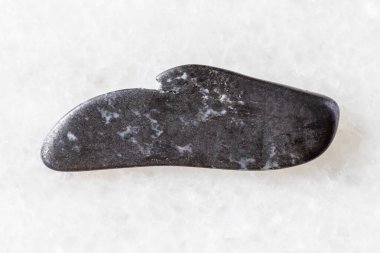 sample of polished braunite mineral on white marble background close up from Liguria, Italy