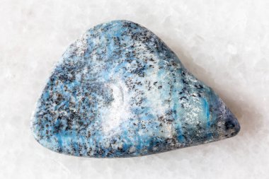 sample of tumbled dianite rock on white marble background close up from Yakutia, Russia