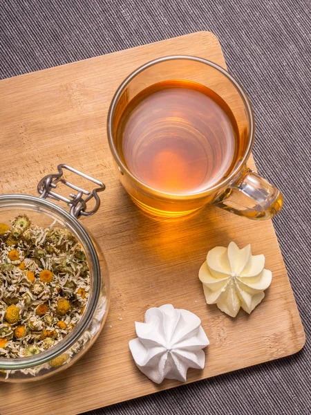 Still life with healthful herbal tea, sweets and wooden cutting board