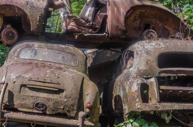 bir depoda yığılmış paslı arabalardan