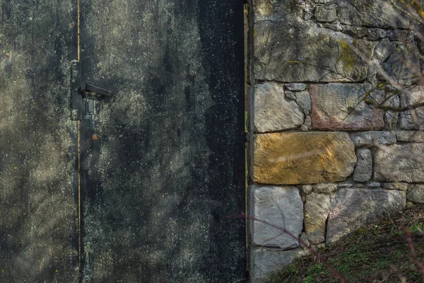 Porta de ferro com uma parede de pedra — Fotografia de Stock