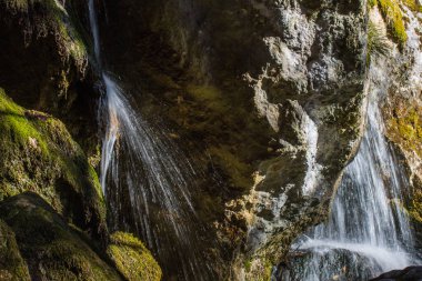 Dağlarda güneşli bir mağarası olan hassas bir su duvarı.