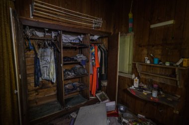 Terk edilmiş bir evde eski kıyafetlerle dolu bir dolap.
