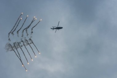 Hava gösterisinde yağmur bulutlu kara bulutlar ve savunma önlemleriyle askeri helikopter.