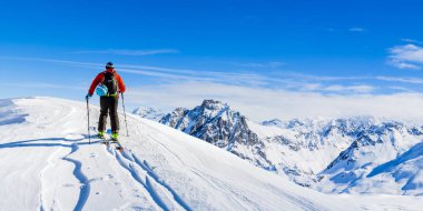 Ski in winter season, mountains and ski touring man on the top in sunny day in France, Alps above the clouds clipart