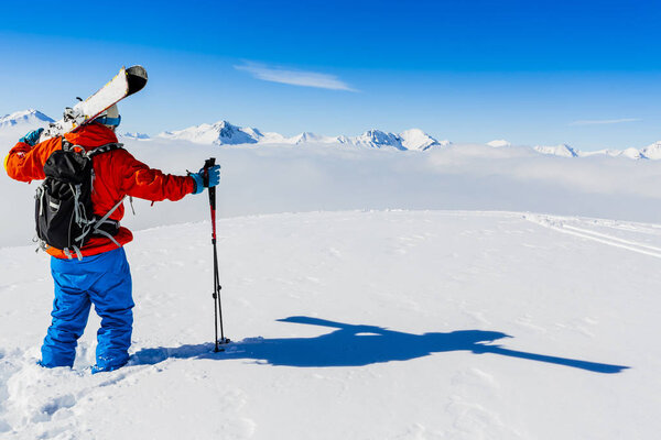 Лыжи в зимний сезон, горы и лыжный турист на вершине в солнечный день во Франции, Альпы над облаками