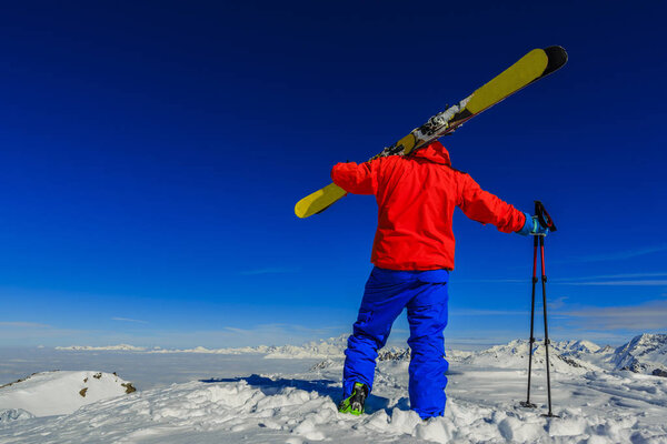 Лыжи в зимний сезон, горы и лыжный турист на вершине в солнечный день во Франции, Альпы над облаками