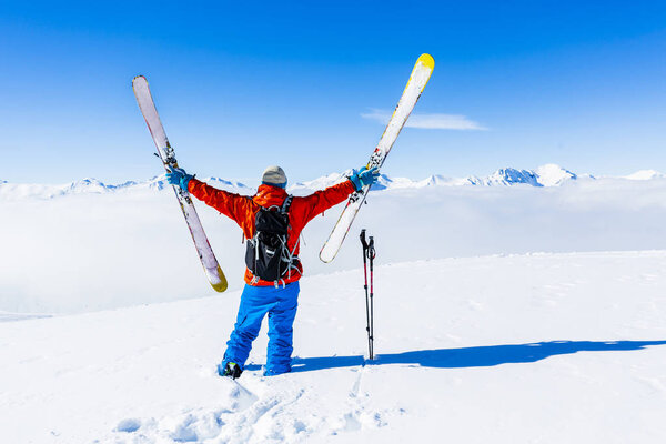 Ski in winter season, mountains and ski touring man on the top in sunny day in France, Alps above the clouds