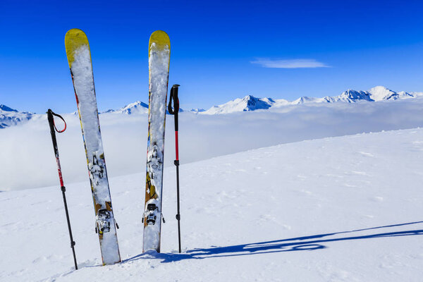 Лыжи в зимний сезон, горы и лыжное снаряжение на вершине в солнечный день во Франции, Альпы над облаками
