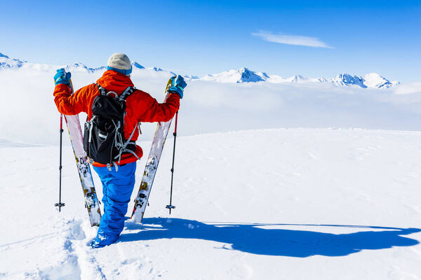 Лыжи в зимний сезон, горы и лыжный турист на вершине в солнечный день во Франции, Альпы над облаками