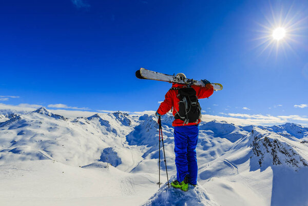 Лыжи в зимний сезон, горы и лыжный турист на вершине в солнечный день во Франции, Альпы над облаками