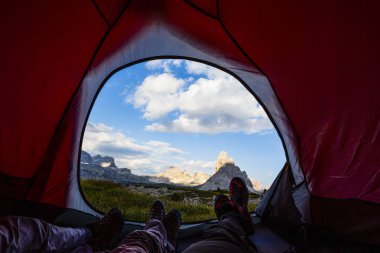 Bivouac at Tre Cime di Lavaredo, family resting in tent, view from inside of the tent on pass in Dolomites, Italy. clipart
