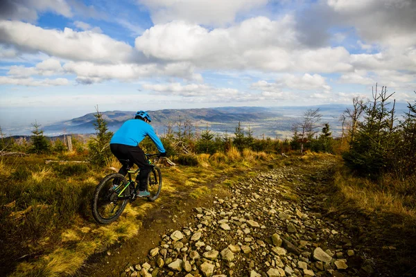 Mountain biker cycling in autumn mountains forest landscape. Man cycling MTB flow trail track. Outdoor sport activity.