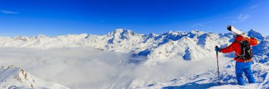 Ski in winter season, mountains and ski touring man on the top in sunny day in France, Alps above the clouds clipart