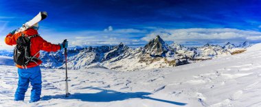 Arka planda Matterhorn, İsviçre Alplerinde Zermatt ile taze toz karda kayak yapan adam..