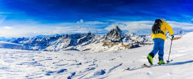 Arka planda Matterhorn, İsviçre Alplerinde Zermatt ile taze toz karda kayak yapan adam..
