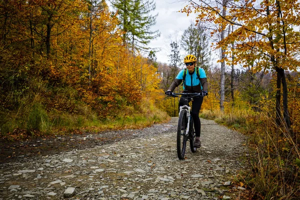 Cycling woman riding on bike in autumn mountains forest landscape. Woman cycling MTB flow trail track. Outdoor sport activity.