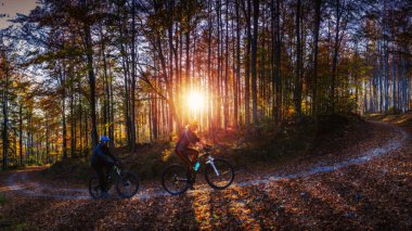 Bisikletli kadın ve erkekler günbatımı dağ manzarasında bisiklet sürüyorlar. Birkaç bisiklet MTB enduro akış yolu. Açık hava sporları aktivitesi.
