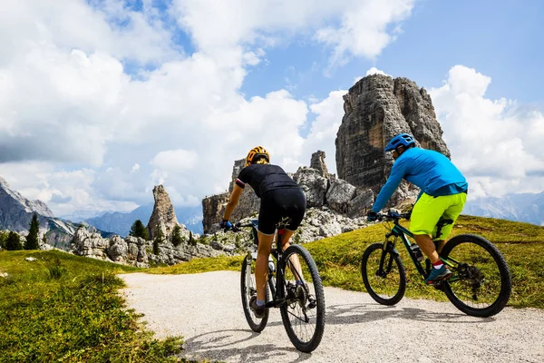 情侣骑自行车在肾上腺皮质激素 Ampezzo 惊人的五加尔达和 Tofana 的背景 妇女和男子骑山地车的踪迹 意大利南蒂罗尔省 白云岩 — 图库照片