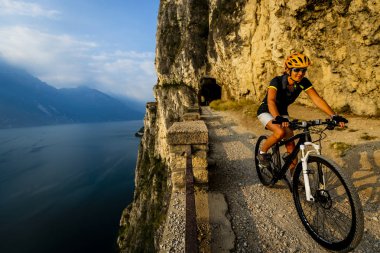 Gündoğumu dağlar ve Garda Gölü manzara motosiklet sürme kadın Bisiklete binme. MTB enduro akışı sentiero ponale iz parça Bisiklete binme. Açık spor aktivitesi.