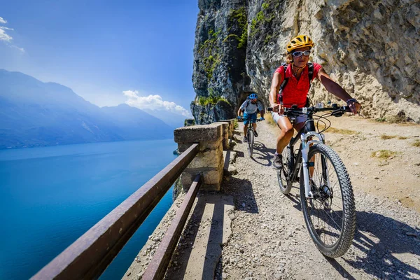 女と男の日の出山とガルダ湖の景色でバイクに乗ってサイクリング Mtb エンデューロ流れ Sentiero Ponale トレイルをサイクリング カップルを追跡します アウトドア スポーツ活動 — ストック写真