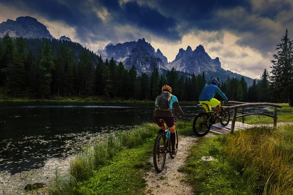 Kerékpáros nő és férfi lovaglás kerékpárok a Dolomitok hegyei és — Stock Fotó