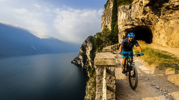 Hombre ciclista a caballo en bicicleta en las montañas del amanecer y el lago de Garda l —  Fotos de Stock