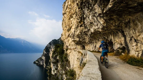 Cycling man riding on bike at sunrise mountains and Garda lake l — Stock Photo, Image