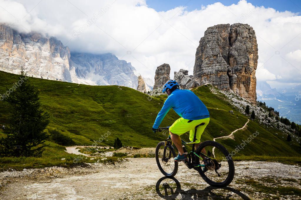 Tourist cycling in Cortina d'Ampezzo, stunning Cinque Torri and 