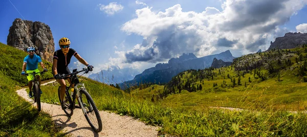 Cycling woman and man riding on bikes in Dolomites mountains lan — Stock Photo, Image