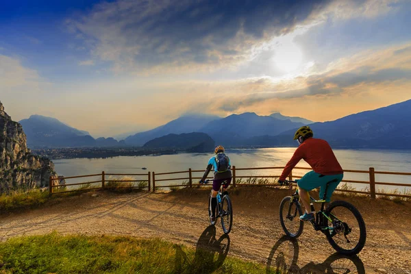 Cycling woman and man riding on bikes at sunrise mountains and G