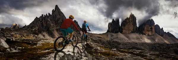 Cycling woman and man riding on bikes in Dolomites mountains and — Stock Photo, Image