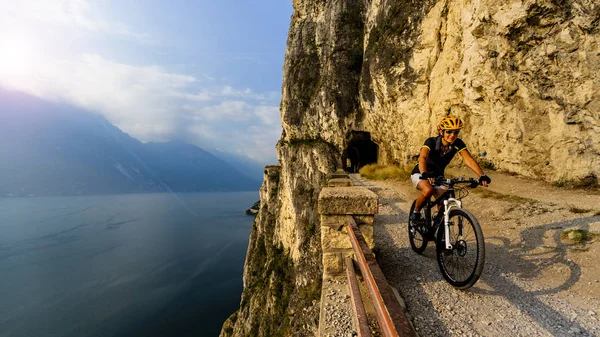 Mountainbikerin bei Sonnenaufgang über dem Gardasee auf Pfad sentier — Stockfoto