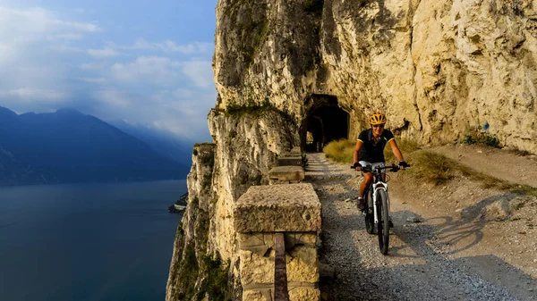 Mountain cykling kvinna vid soluppgången över Gardasjön på väg Sentier — Stockfoto