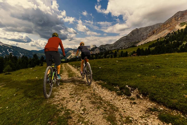 Cycling woman and man riding on bikes in Dolomites mountains and — Stock Photo, Image