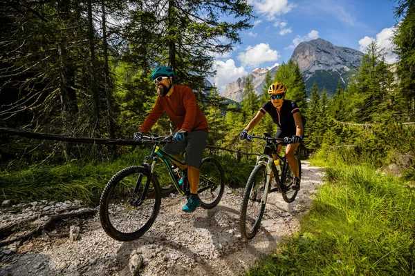 Cycling woman and man riding on bikes in Dolomites mountains and — Stock Photo, Image