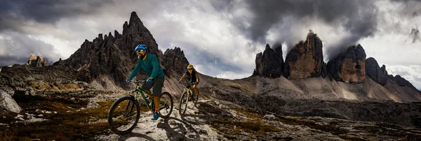 Cycling woman and man riding on bikes in Dolomites mountains and — Stock Photo, Image