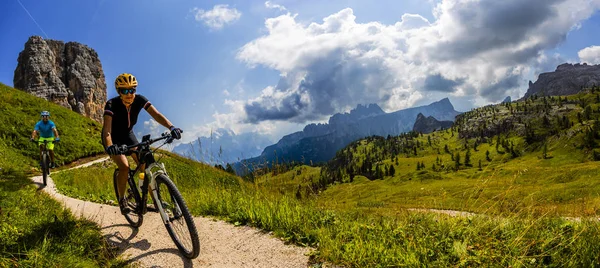 Cykling kvinna och man rider på cyklar i Dolomiterna lan — Stockfoto