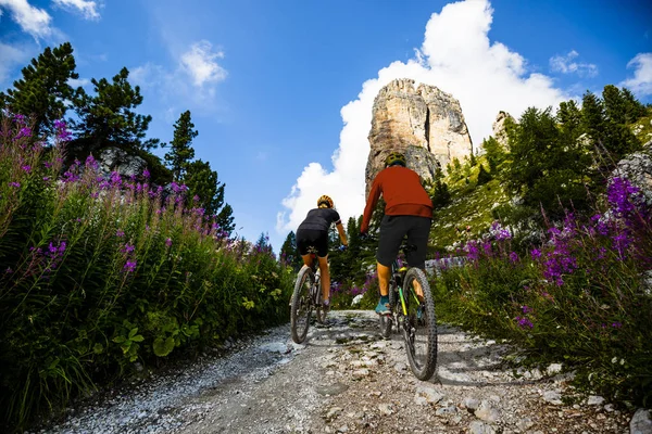 Cycling woman and man riding on bikes in Dolomites mountains lan