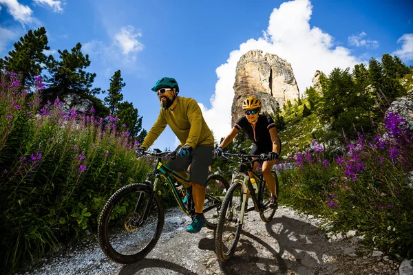 Cycling woman and man riding on bikes in Dolomites mountains lan