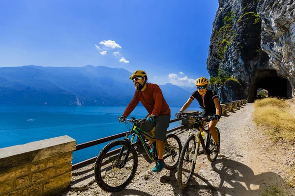 Cycling woman and man riding on bikes at sunrise mountains and G