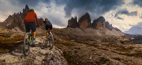 Cycling woman and man riding on bikes in Dolomites mountains and — Stock Photo, Image