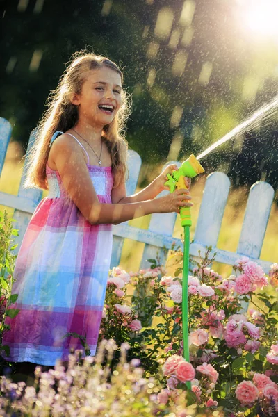 Playfull menina regando flores com chuva no jardim no verão — Fotografia de Stock